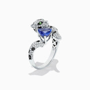 The Signature 14K White Gold Tanzanite and Diamond Panther Ring, 2.07 TCW, features black spots, green eyes, and a blue heart-shaped tanzanite gemstone held in the panther’s mouth.