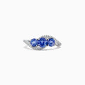 The Nahla Siri 14K White Gold Tanzanite and Diamond Ring, 1.63 TCW, showcases three round tanzanites at the center with curved rows of sparkling white diamonds on each side, all displayed against a white background.