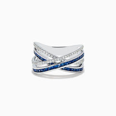 The 14K White Gold Blue Sapphire and Diamond Crossover Ring features overlapping bands adorned with sparkling diamonds and vivid blue sapphires in an elegant crisscross design, shown on a white background.