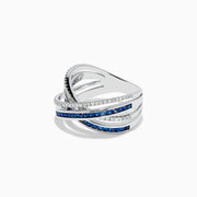 The 14K White Gold Blue Sapphire and Diamond Crossover Ring features overlapping bands adorned with sparkling diamonds and vivid blue sapphires in an elegant crisscross design, shown on a white background.