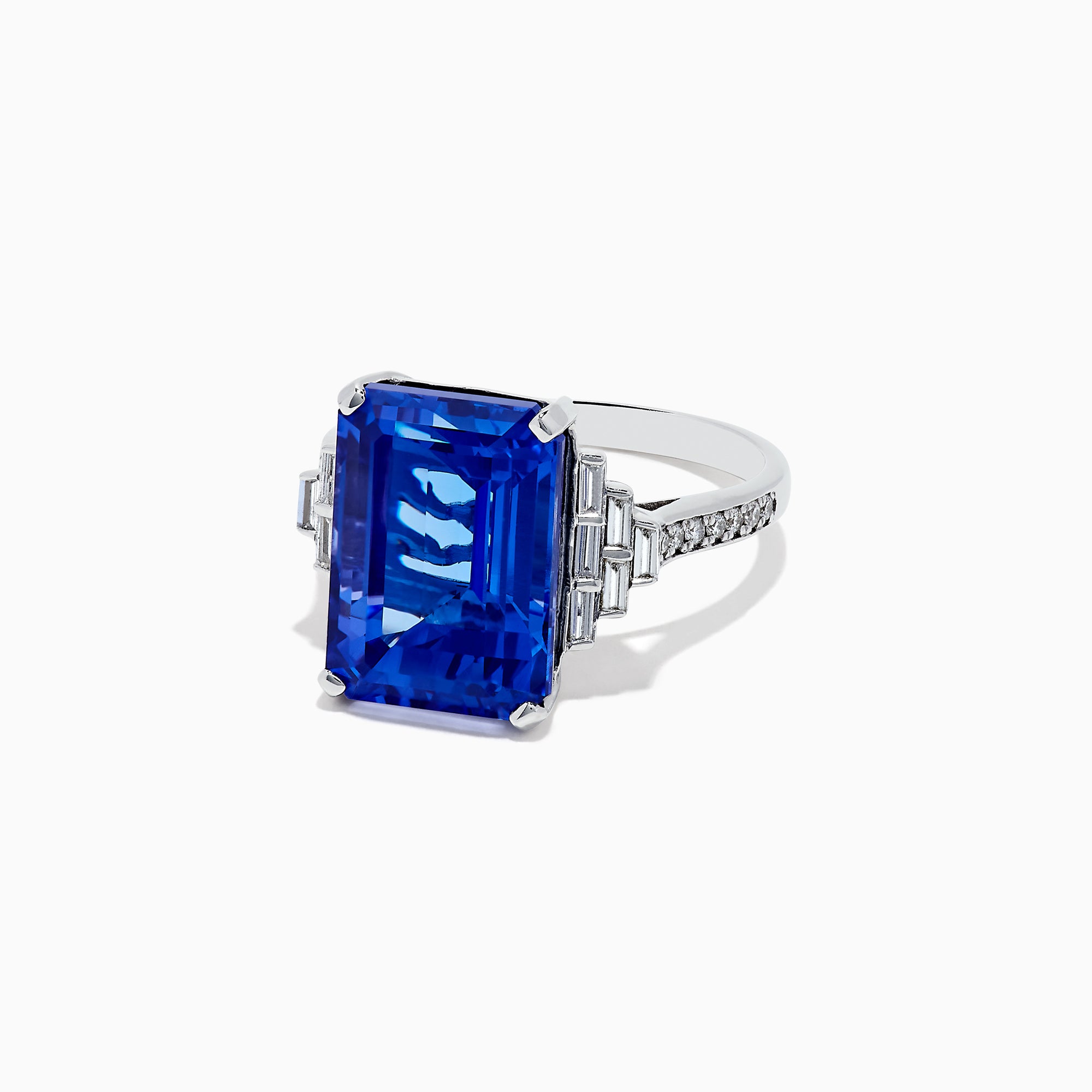 The 14K White Gold Tanzanite and Diamond Cocktail Ring, 7.83 TCW, features a large rectangular blue tanzanite with step-cut facets, accented by geometric clusters of sparkling diamonds on each side, showcased against a white background.