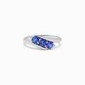 The Nahla Siri Sterling Silver Tanzanite and Diamond Ring (0.86 TCW) showcases three round tanzanites set side by side in a modern overlapping band, displayed on a white background.