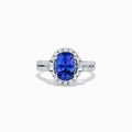 The 14K White Gold Tanzanite and Diamond Ring, 3.03 TCW, features an oval blue tanzanite center stone encircled by a halo of diamonds and additional diamonds set on the band.