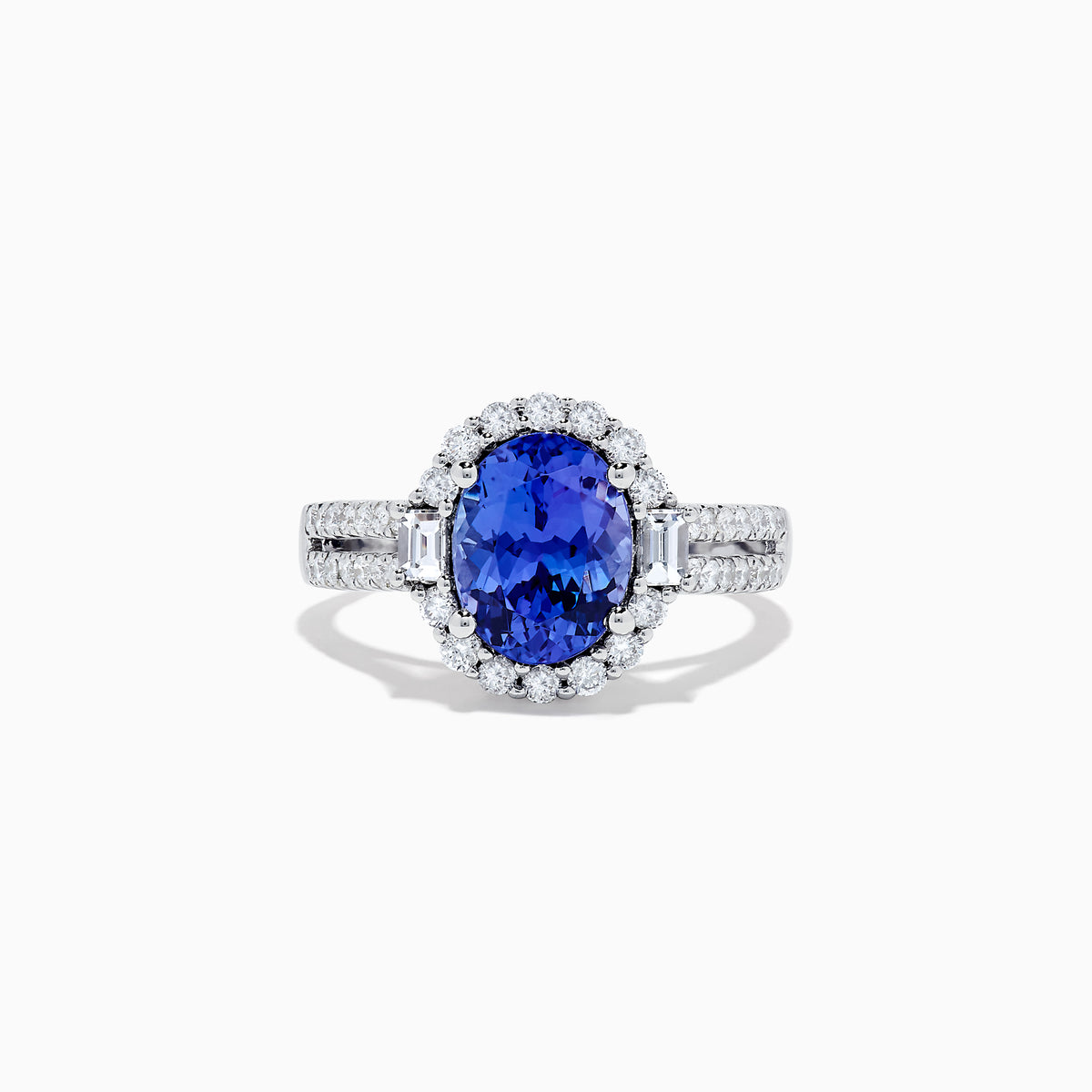 The 14K White Gold Tanzanite and Diamond Ring, 3.03 TCW, features an oval blue tanzanite center stone encircled by a halo of diamonds and additional diamonds set on the band.