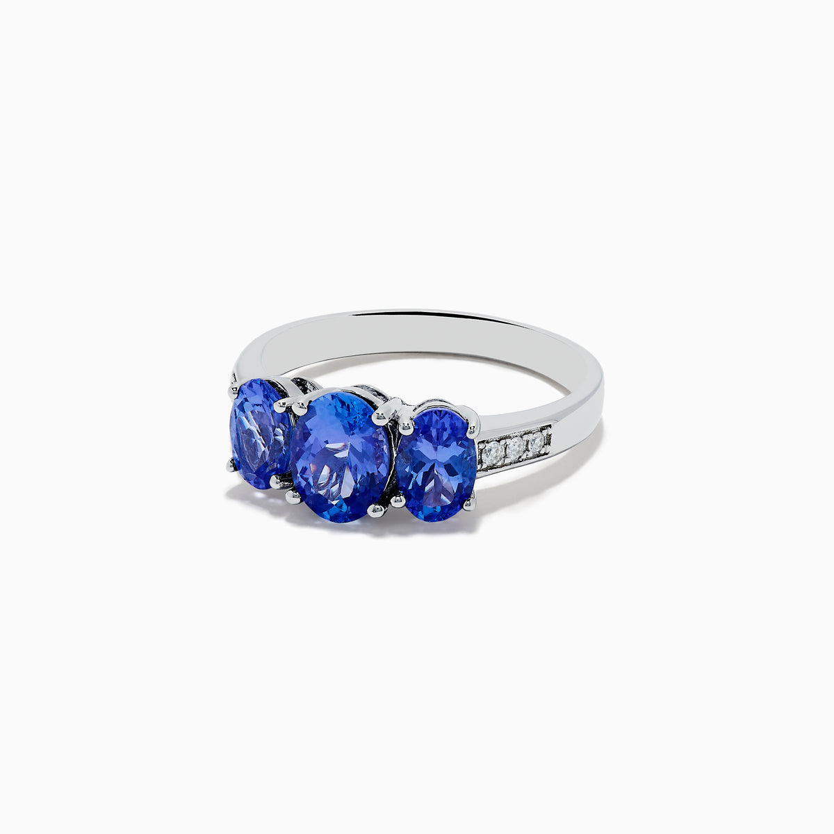 The Nahla Siri Sterling Silver Diamond and Tanzanite Ring features three oval-cut blue gemstones at the center, flanked by diamond accents on each side of the band, shown against a white background.