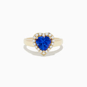 The Nahla Siri 14K Yellow Gold Tanzanite and Diamond Heart Ring, featuring a heart-shaped blue tanzanite surrounded by round white diamonds, is shown against a plain white background.
