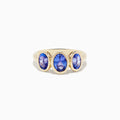 The Nahla Siri 14K Yellow Gold Tanzanite Three Stone Ring features three oval blue tanzanites in bezel settings on a simple gold band.