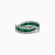 A 14K White Gold Princess Cut Emerald and Diamond Ring, 1.76 TCW, features two overlapping bands with rectangular green emeralds at the center bordered by small diamonds, displayed against a white background.
