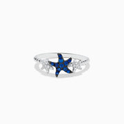 The Seaside 14K White Gold Sapphire and Diamond Starfish Ring showcases a blue sapphire and diamond starfish center, accented by two small clear gemstone fish shapes on each side, all set in white gold.