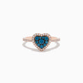 The Bella Bleu 14K Rose Gold Blue and White Diamond Heart Ring features a heart-shaped cluster of blue and white diamonds, accented by a border of clear stones and more clear stones set on the band.