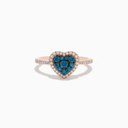 The Bella Bleu 14K Rose Gold Blue and White Diamond Heart Ring features a heart-shaped cluster of blue and white diamonds, accented by a border of clear stones and more clear stones set on the band.